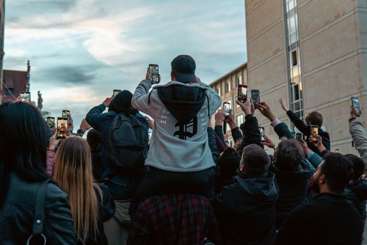 A crowd of people taking pictures with their cell phones